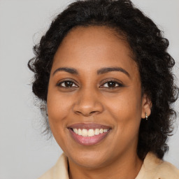 Joyful black adult female with long  brown hair and brown eyes