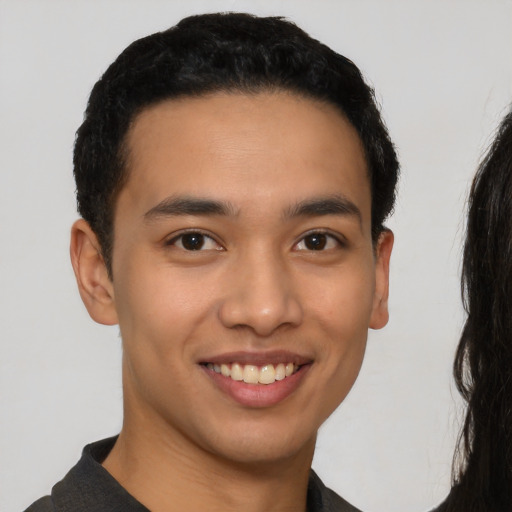 Joyful latino young-adult male with short  brown hair and brown eyes