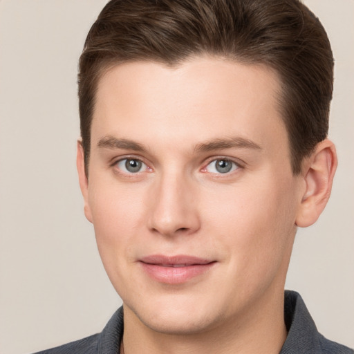 Joyful white young-adult male with short  brown hair and grey eyes