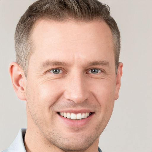 Joyful white young-adult male with short  brown hair and grey eyes