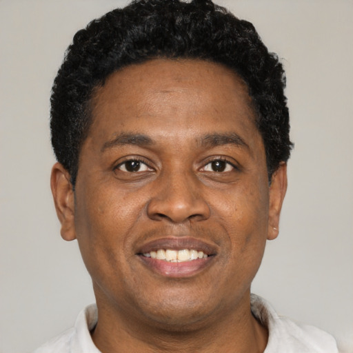 Joyful black young-adult male with short  brown hair and brown eyes