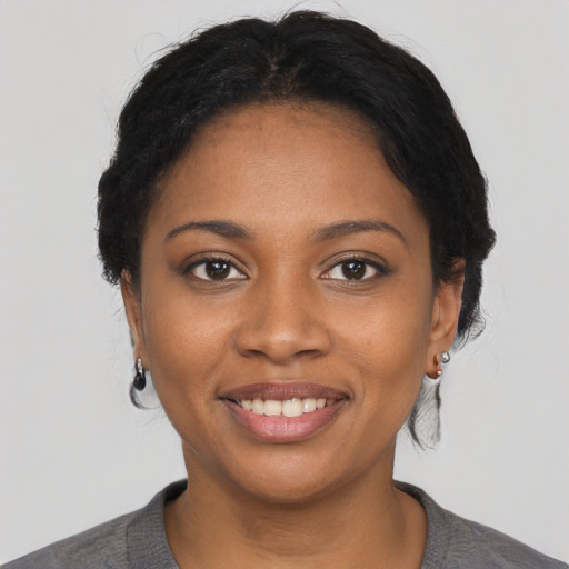 Joyful black young-adult female with short  black hair and brown eyes