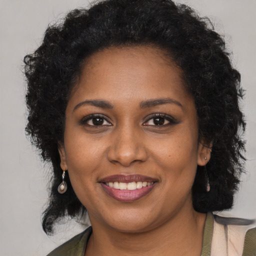 Joyful black young-adult female with long  brown hair and brown eyes
