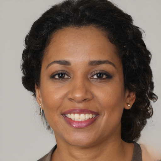 Joyful black adult female with medium  brown hair and brown eyes