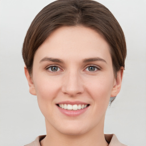 Joyful white young-adult female with short  brown hair and grey eyes