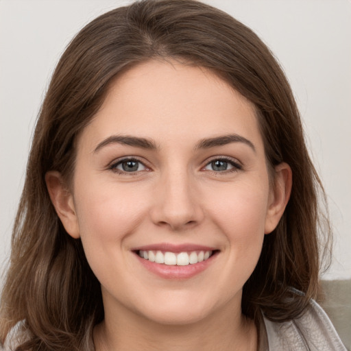 Joyful white young-adult female with medium  brown hair and grey eyes