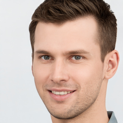 Joyful white young-adult male with short  brown hair and grey eyes