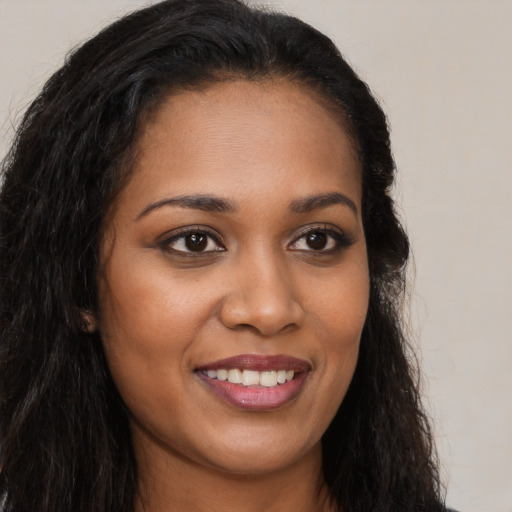 Joyful black young-adult female with long  brown hair and brown eyes