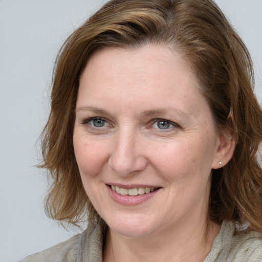 Joyful white adult female with medium  brown hair and blue eyes