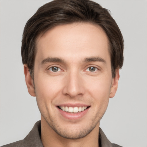 Joyful white young-adult male with short  brown hair and grey eyes