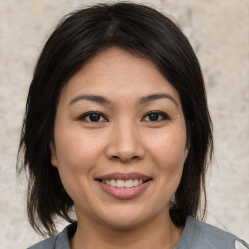 Joyful asian young-adult female with medium  brown hair and brown eyes