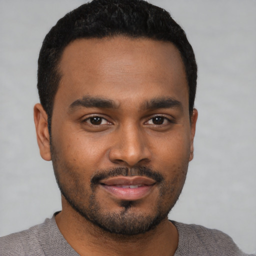 Joyful black young-adult male with short  black hair and brown eyes