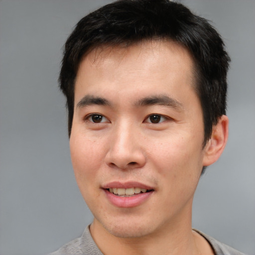 Joyful asian young-adult male with short  black hair and brown eyes