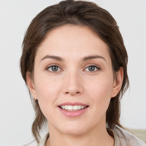 Joyful white young-adult female with medium  brown hair and grey eyes