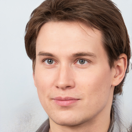 Joyful white young-adult male with medium  brown hair and grey eyes