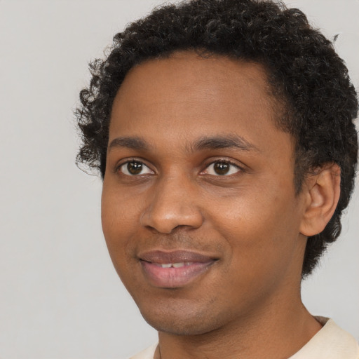 Joyful black young-adult male with short  brown hair and brown eyes
