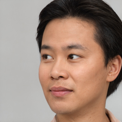 Joyful asian young-adult male with short  brown hair and brown eyes