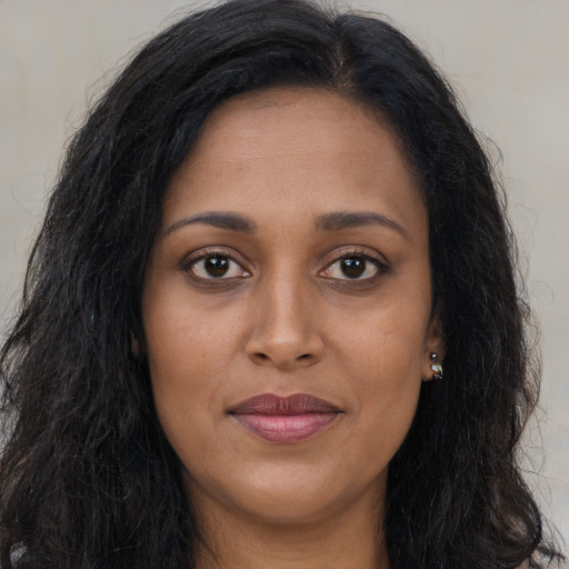 Joyful black young-adult female with long  brown hair and brown eyes