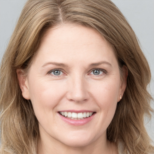 Joyful white adult female with long  brown hair and grey eyes