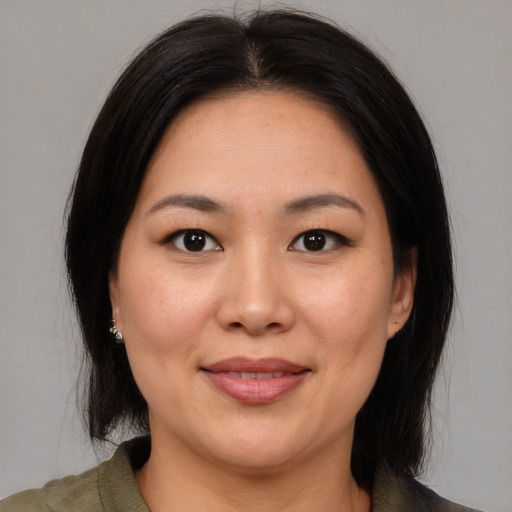 Joyful asian adult female with medium  brown hair and brown eyes