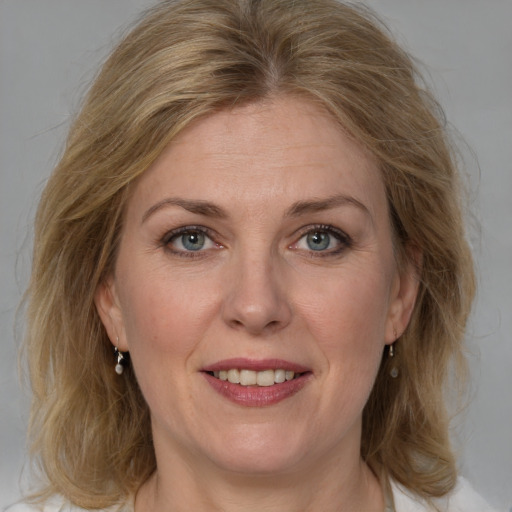 Joyful white adult female with medium  brown hair and blue eyes