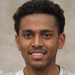 Joyful black young-adult male with short  brown hair and brown eyes