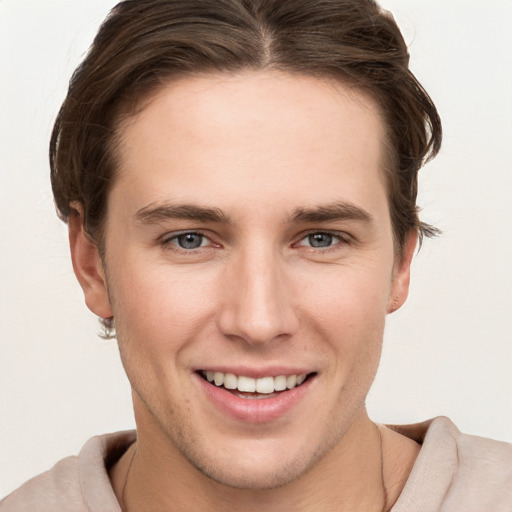 Joyful white young-adult male with short  brown hair and grey eyes