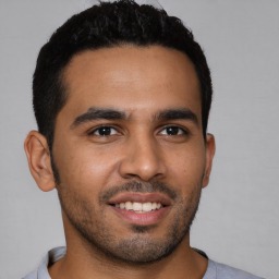 Joyful latino young-adult male with short  brown hair and brown eyes