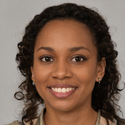 Joyful black young-adult female with long  brown hair and brown eyes