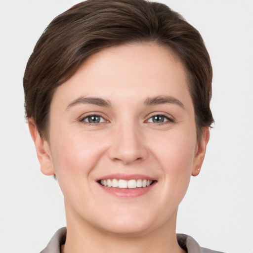 Joyful white young-adult female with short  brown hair and grey eyes