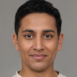 Joyful latino young-adult male with short  brown hair and brown eyes