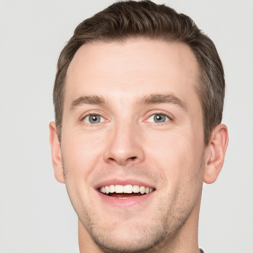 Joyful white young-adult male with short  brown hair and grey eyes