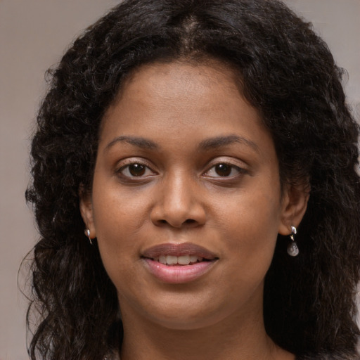 Joyful black young-adult female with long  brown hair and brown eyes