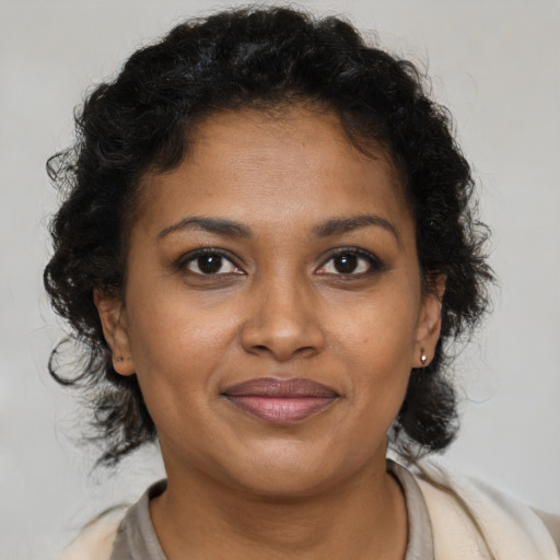 Joyful black young-adult female with long  brown hair and brown eyes