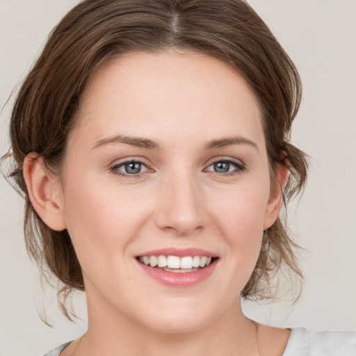 Joyful white young-adult female with medium  brown hair and grey eyes