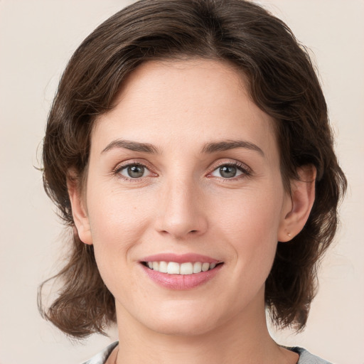 Joyful white young-adult female with medium  brown hair and grey eyes