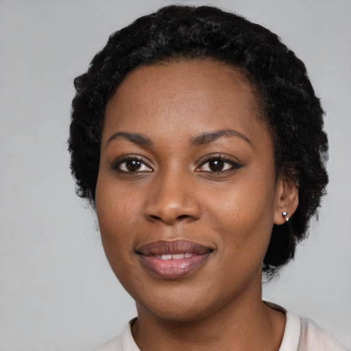 Joyful black young-adult female with short  black hair and brown eyes