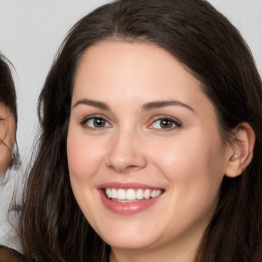 Joyful white young-adult female with long  brown hair and brown eyes