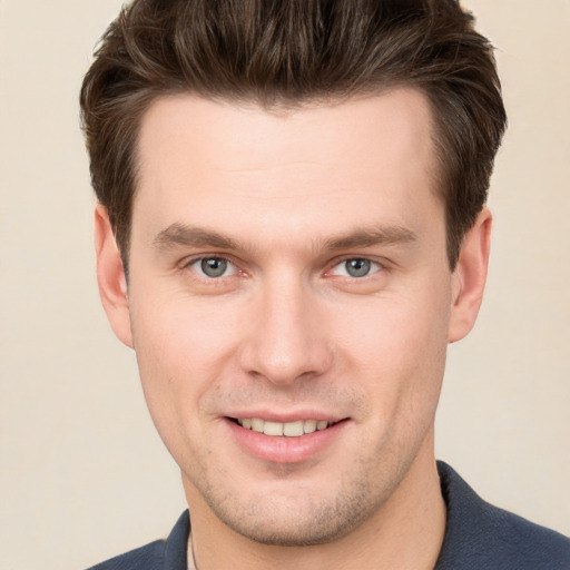 Joyful white young-adult male with short  brown hair and grey eyes