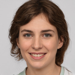 Joyful white young-adult female with medium  brown hair and green eyes