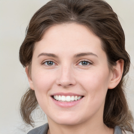 Joyful white young-adult female with medium  brown hair and grey eyes