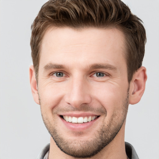 Joyful white young-adult male with short  brown hair and grey eyes