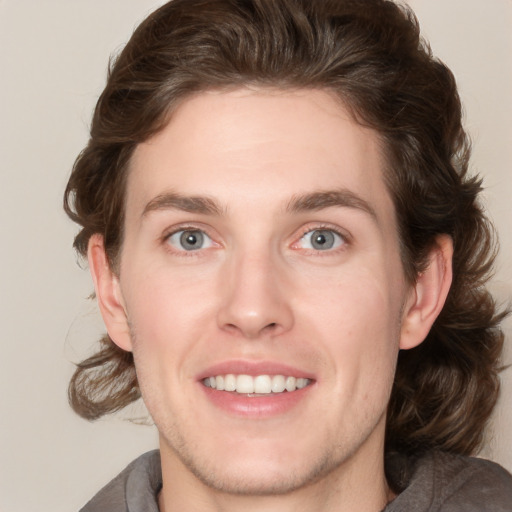 Joyful white young-adult male with medium  brown hair and grey eyes