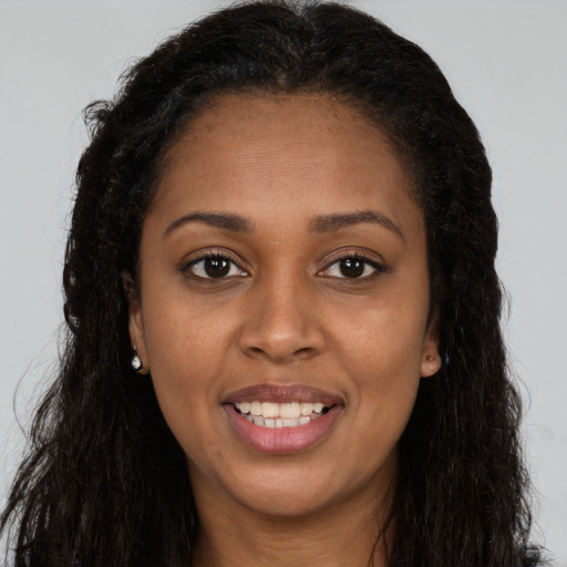 Joyful black young-adult female with long  brown hair and brown eyes