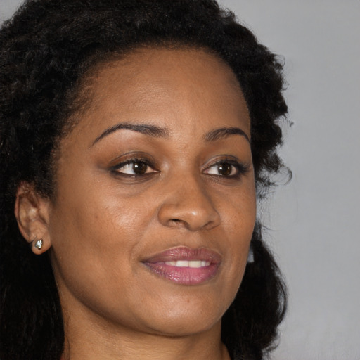 Joyful black young-adult female with long  brown hair and brown eyes