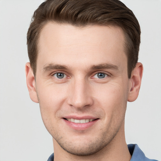 Joyful white young-adult male with short  brown hair and grey eyes