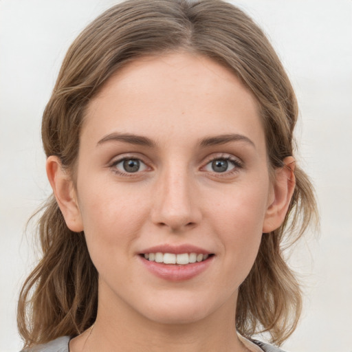 Joyful white young-adult female with medium  brown hair and grey eyes