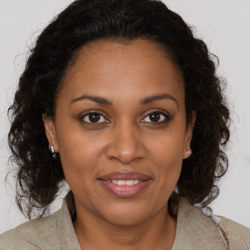 Joyful black young-adult female with long  brown hair and brown eyes