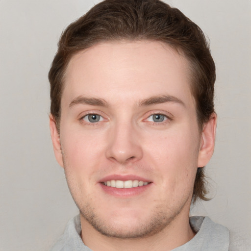 Joyful white young-adult male with short  brown hair and grey eyes