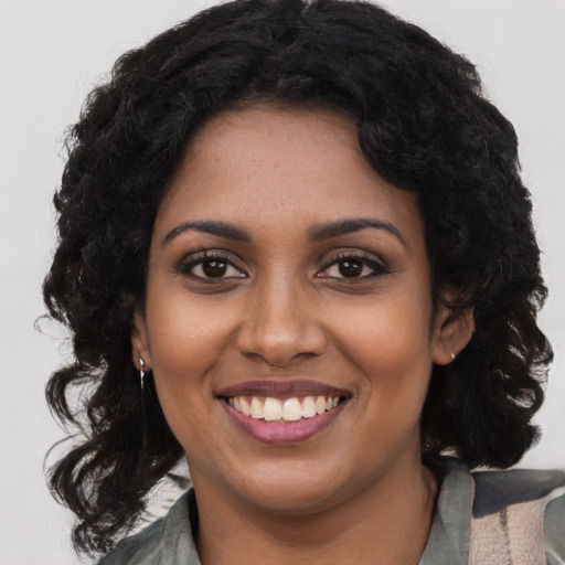 Joyful black young-adult female with long  brown hair and brown eyes